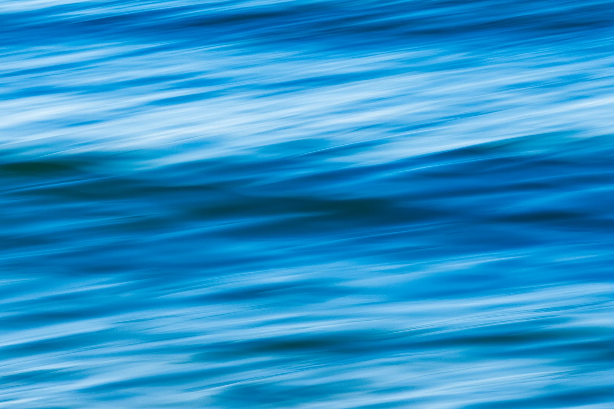 Abstract blue water with diagonal light streaks and a dark undulating wave.