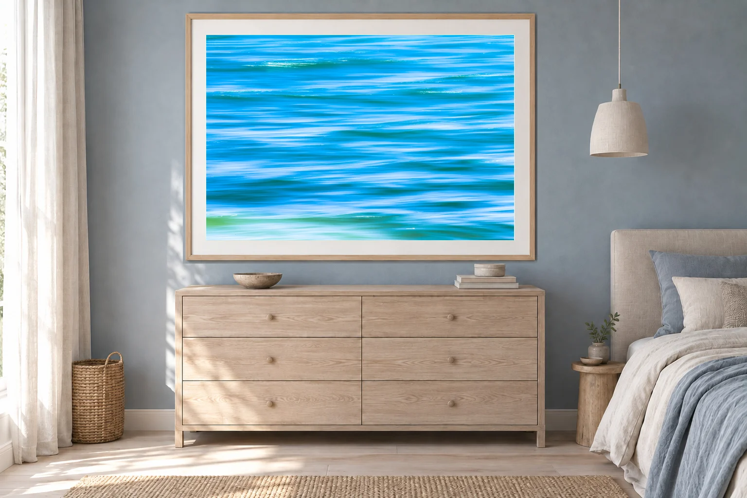 Illustrative mockup: original The Water Writes photograph, 100 cm wide, in a maple frame with a white mat above a chest in a blue-grey bedroom.