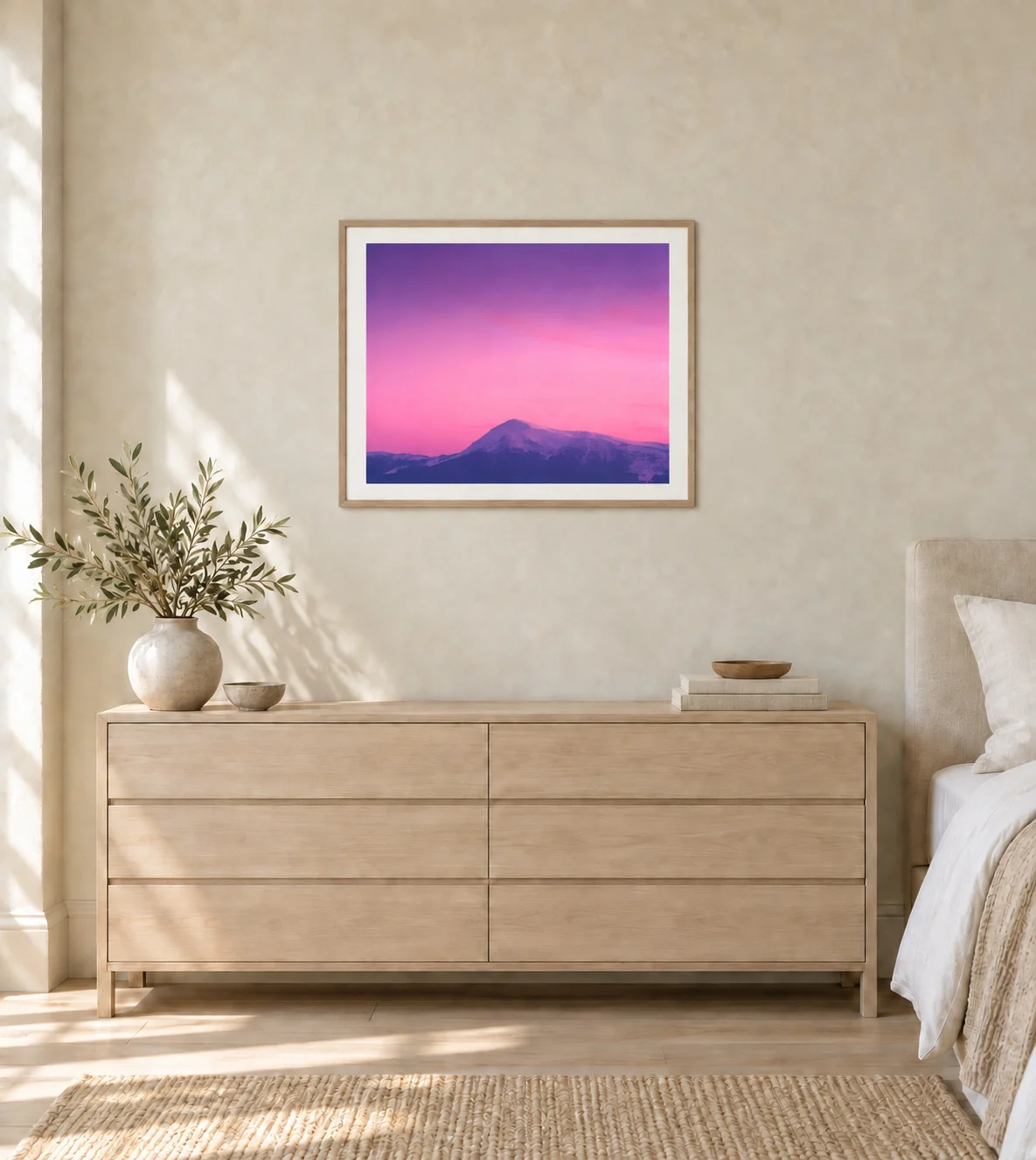 Illustrative mockup of the framed mountain photograph with a warm-white mat above an ash dresser in a pale contemporary bedroom.