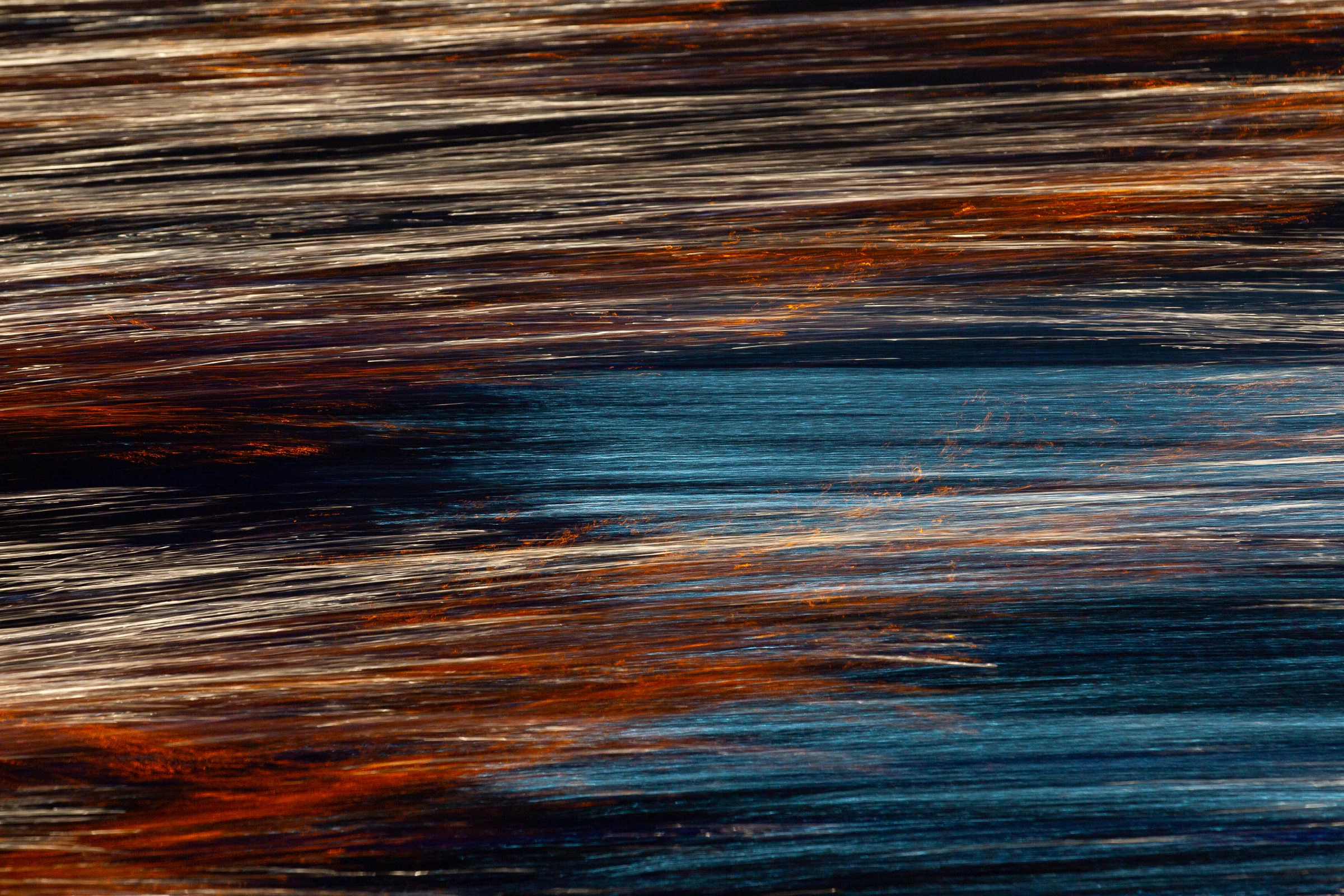 Copper-orange and silver streaks crossing layered bands of deep blue and black.